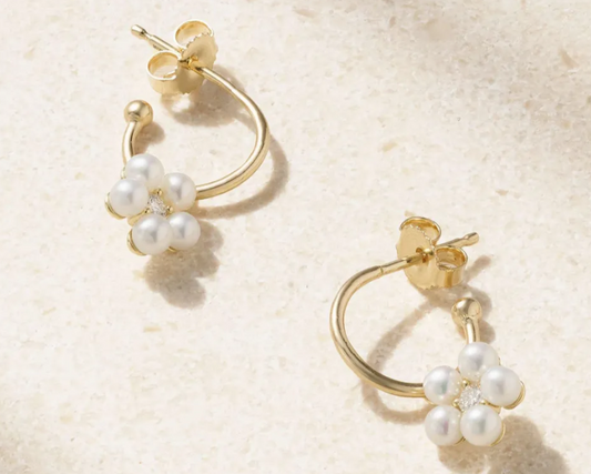 Gold hoop earrings with pearl-like beads on a beige background